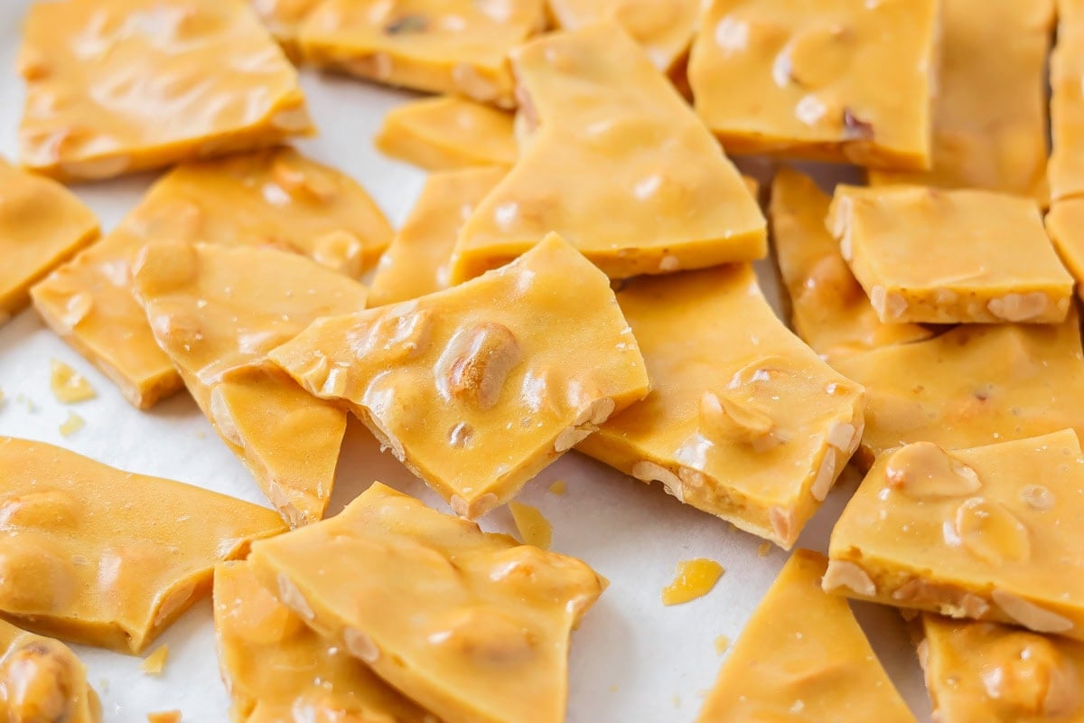 Easy Peanut brittle recipe broken into pieces on parchment paper.