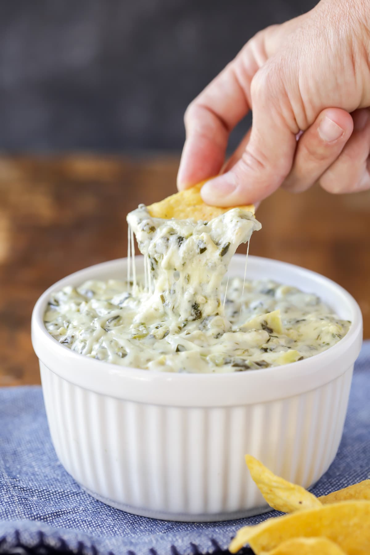 Dipping a chip into hot spinach artichoke dip.