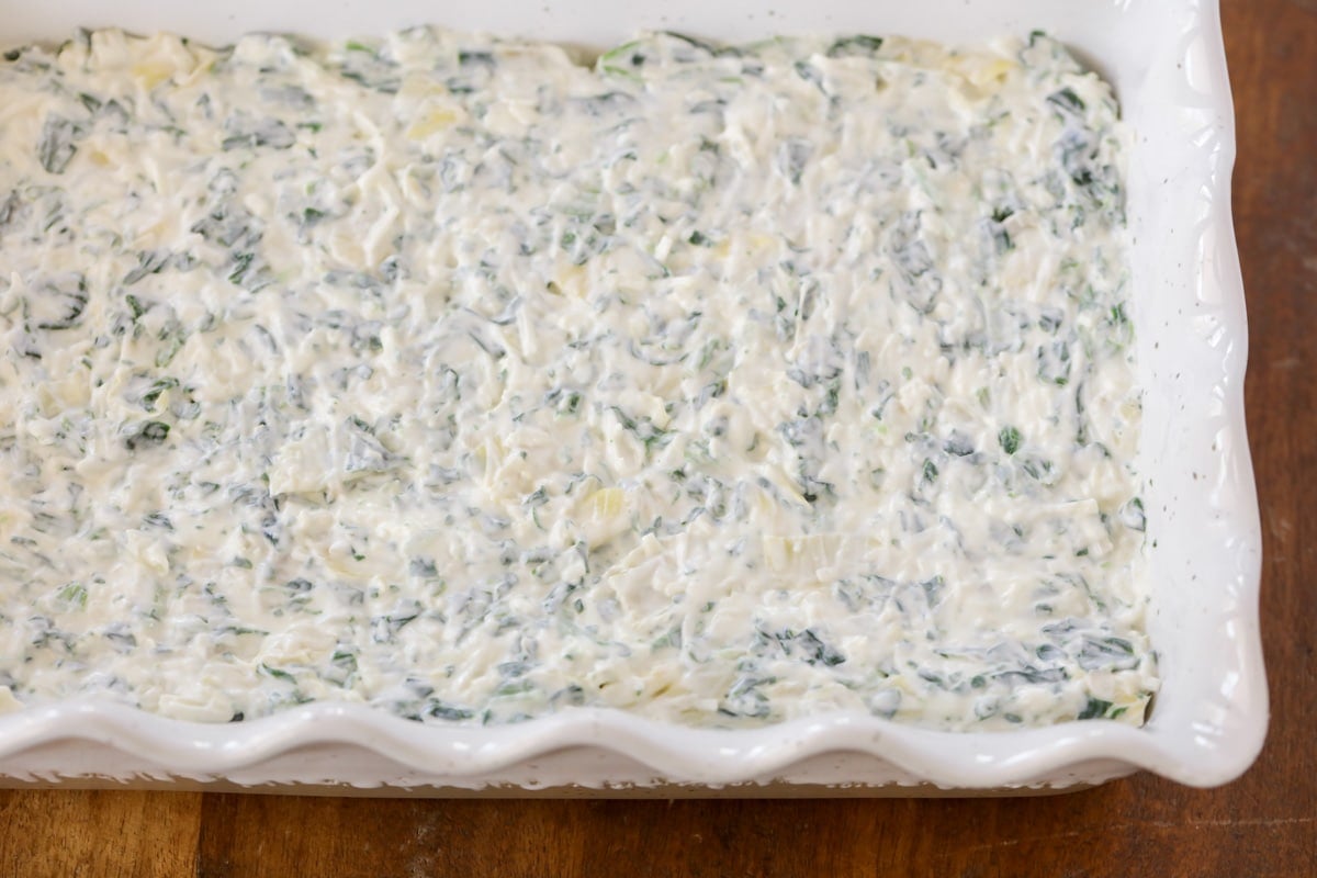 Baked spinach artichoke dip in a white baking dish.
