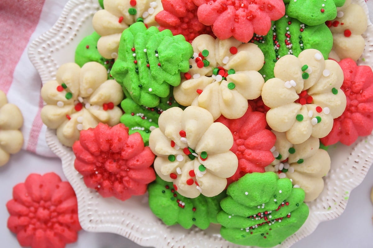 Christmas colored spritz cookies piled onto a plate.