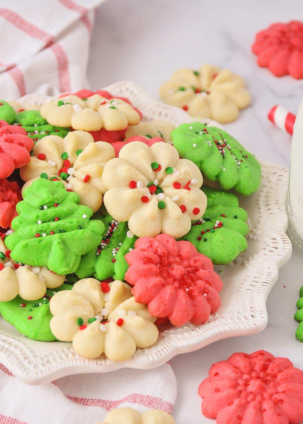 Christmas colored spritz cookies piled onto a white plate.