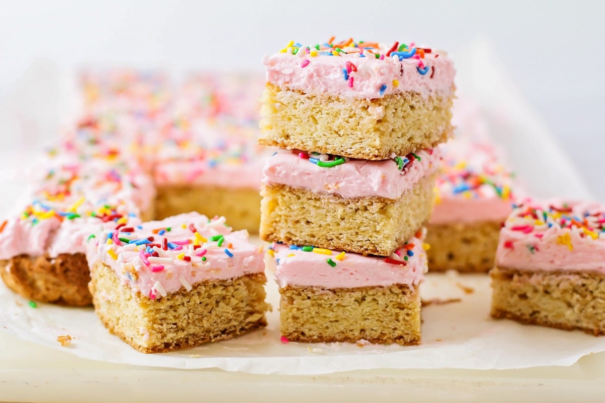 Dessert Bar Recipes - Sugar Cookie Bars with pink frosting and rainbow sprinkles on a white plate. 