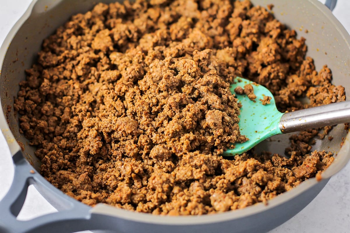 Ground beef seasoned with taco seasoning in a skillet. 