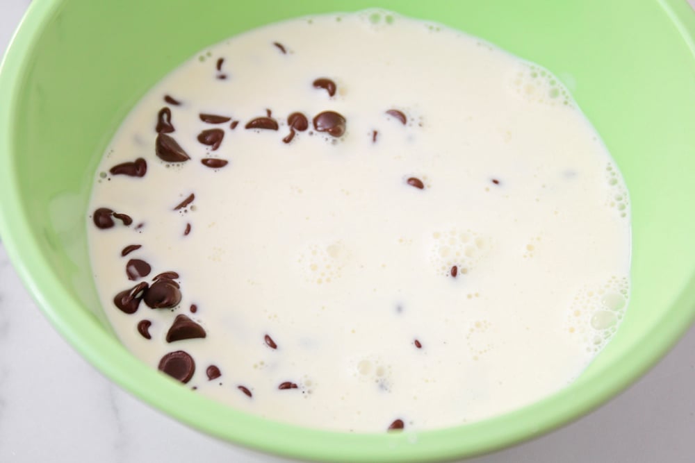 Milk and chocolate chips in a green bowl.