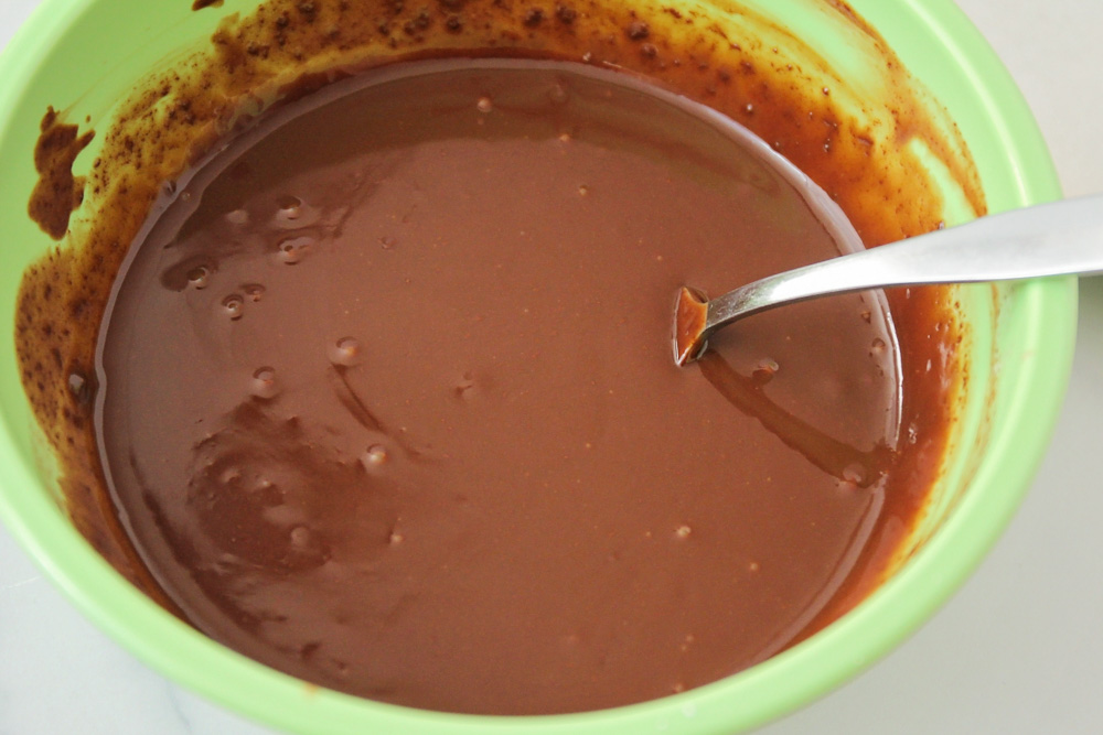 Melting chocolate ganache in a green bowl.
