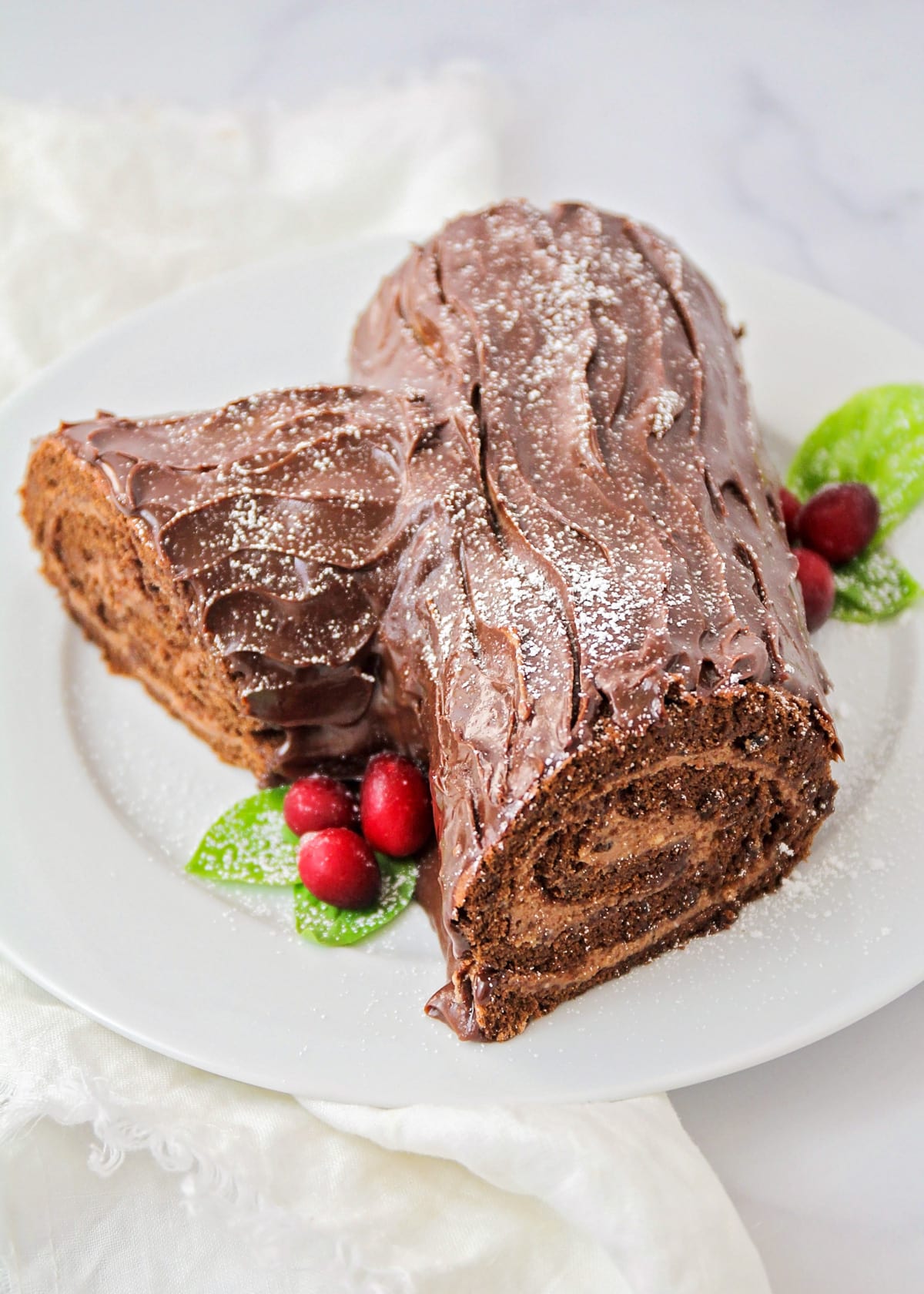 A decorated yule log cake served on a white plate.