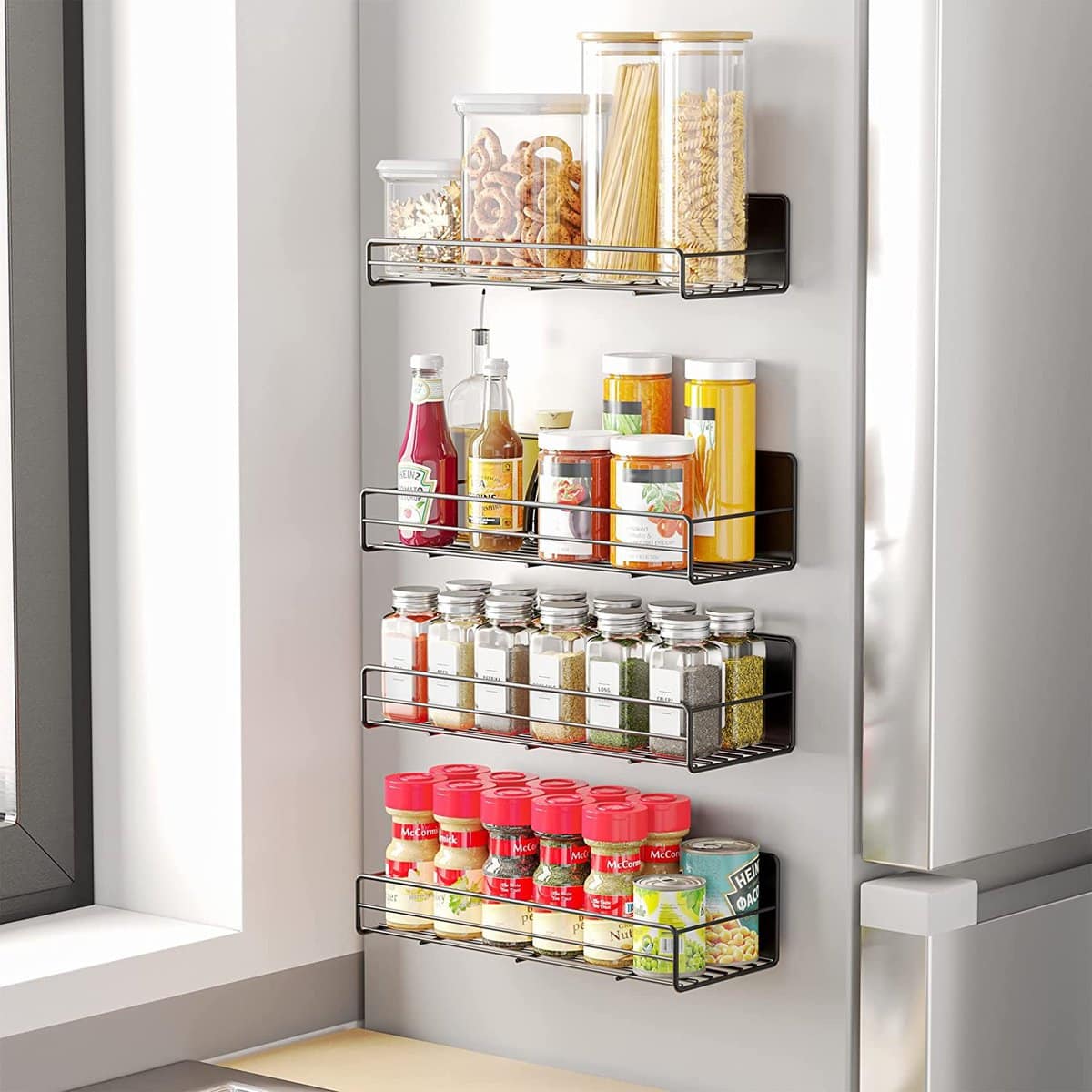 Kitchen organization ideas - Four magnetic metal racks on the side of a fridge holding several spices.
