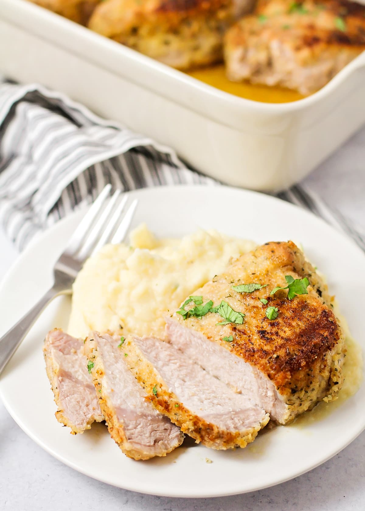 Breaded pork chops partially sliced and served with mashed potatoes.