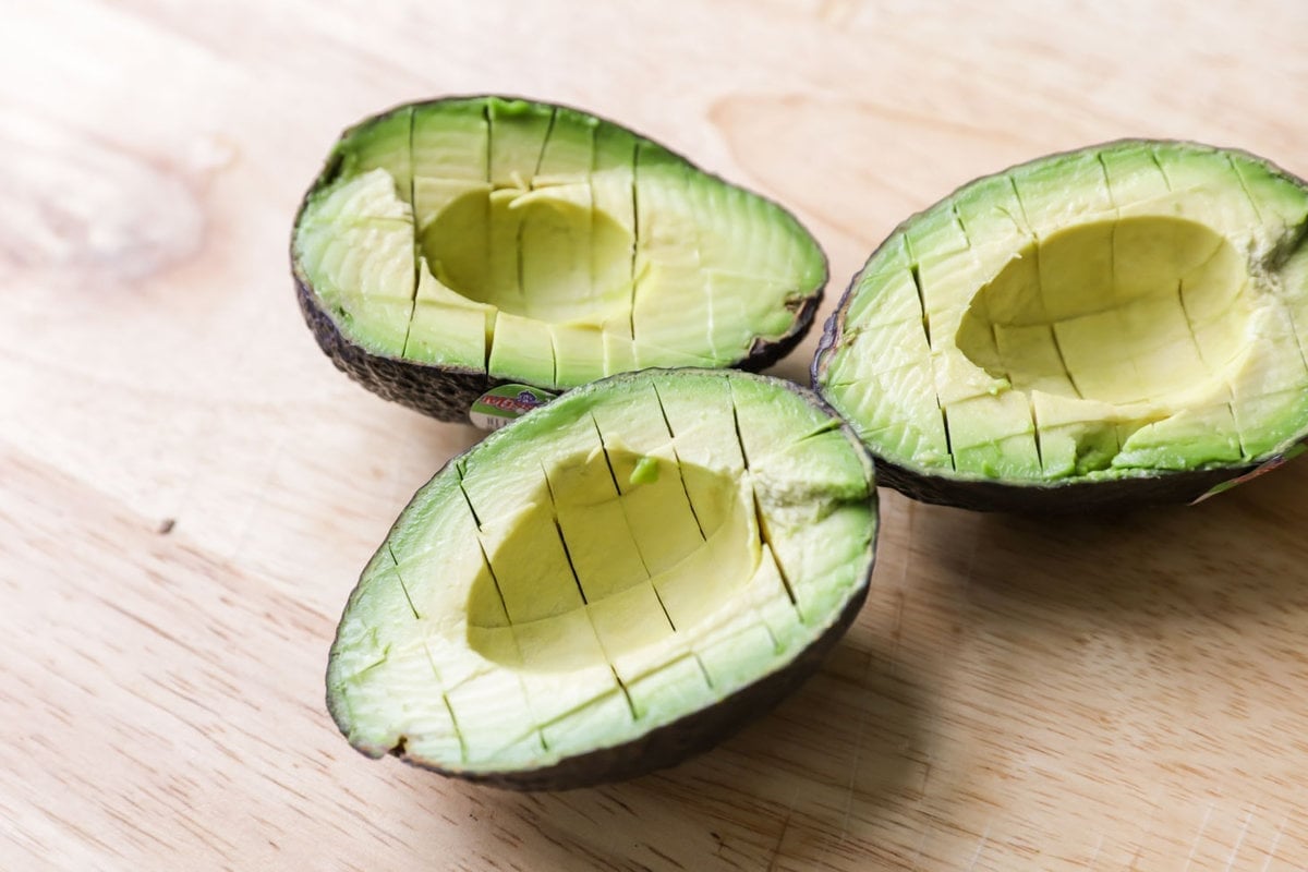 Avocado diced in the peel on a counter.