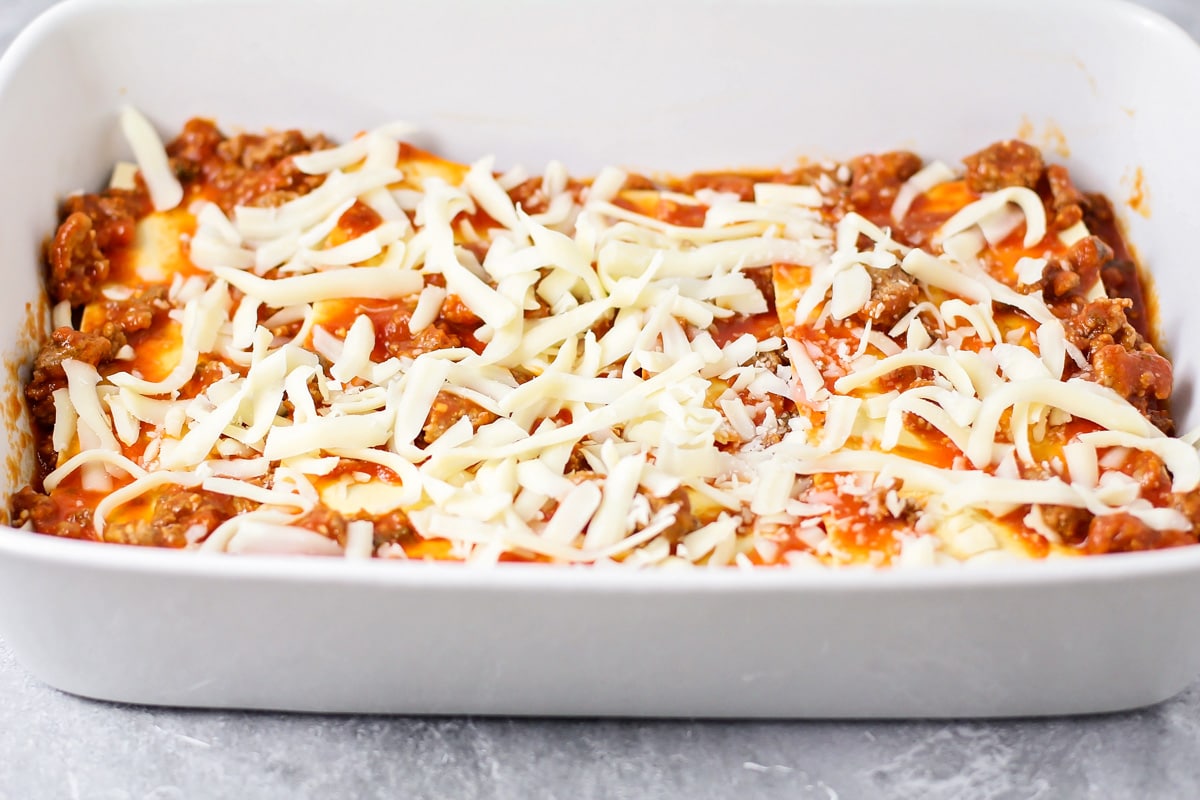 Layering sauce, pasta, and cheese for easy lasagna recipe.
