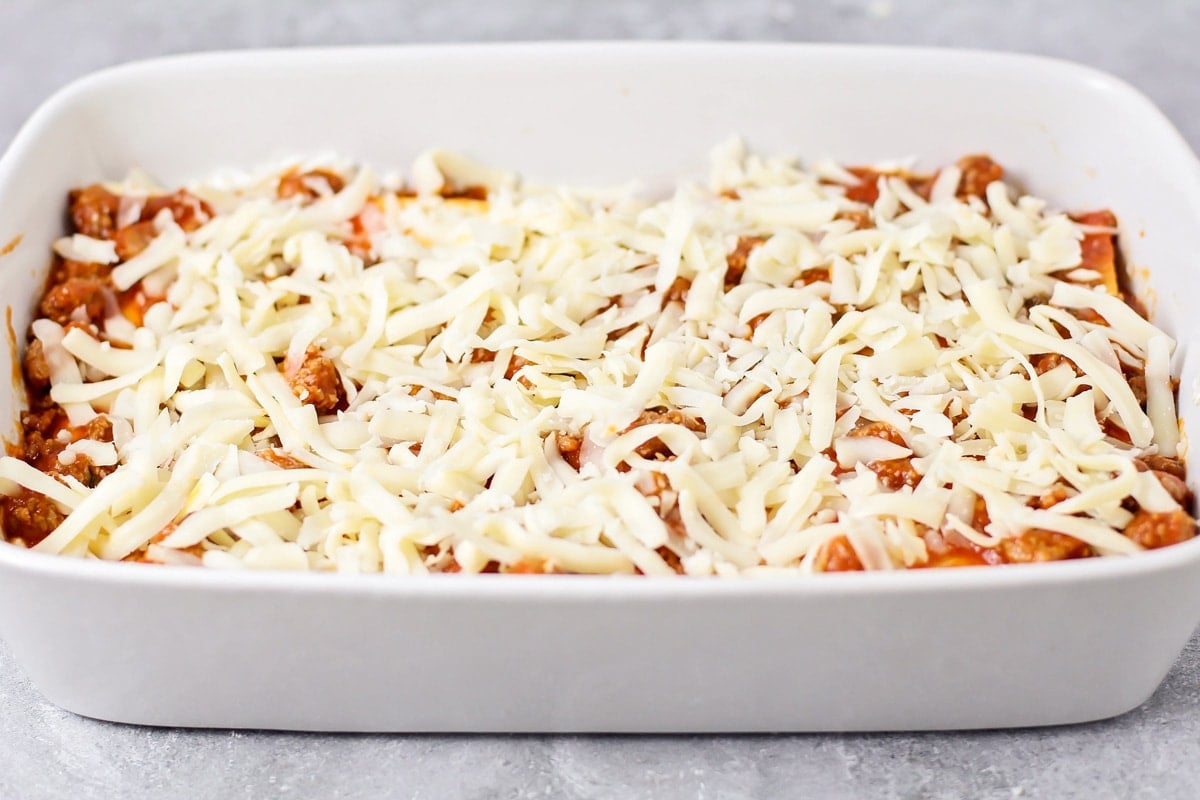 Layering sauce, pasta, and cheese for easy lasagna recipe.