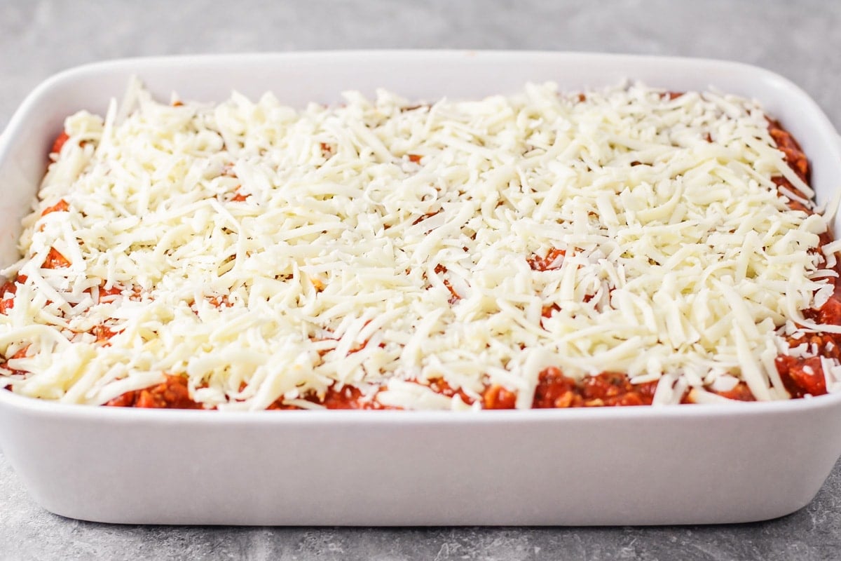 Homemade lasagna toped with a layer of mozzarella and ready to be baked.