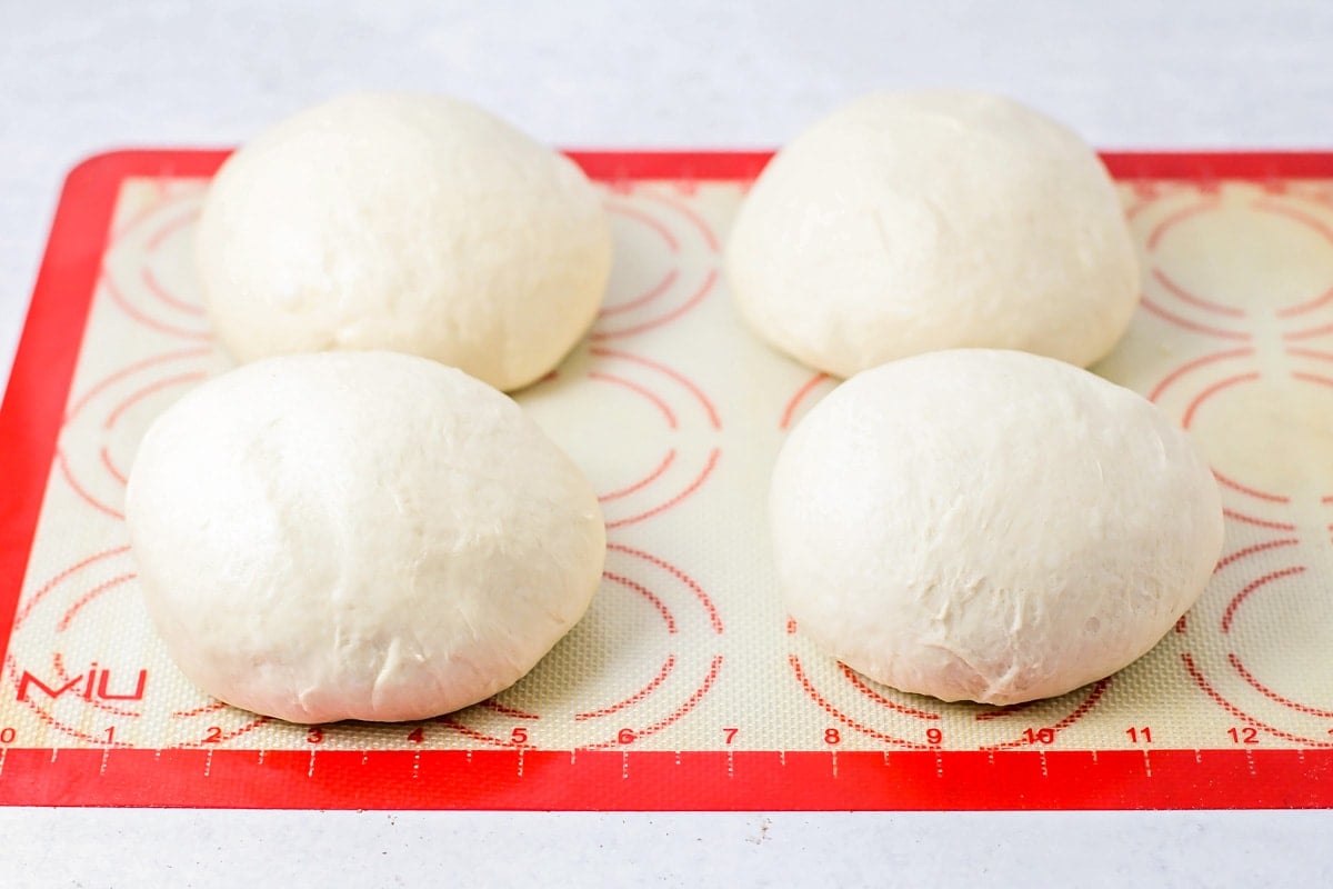 Homemade pizza dough divided into four dough balls.