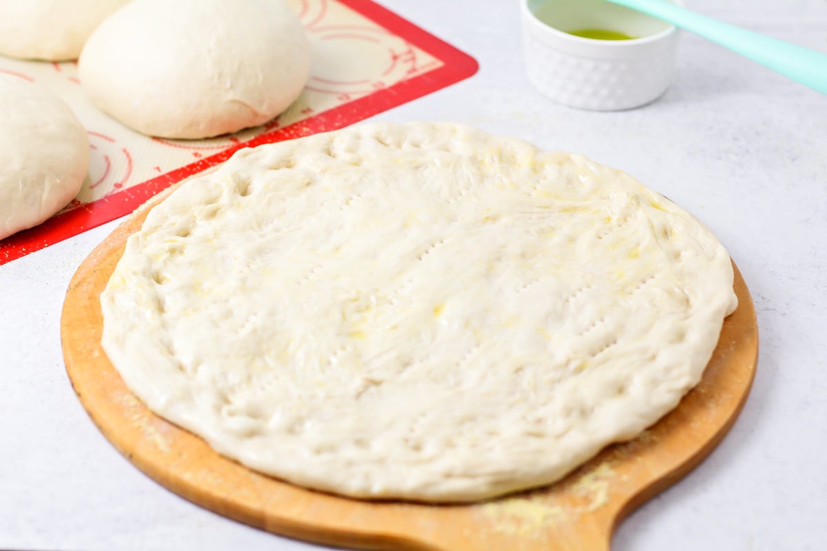 Homemade pizza dough spread and served on a pizza peel.
