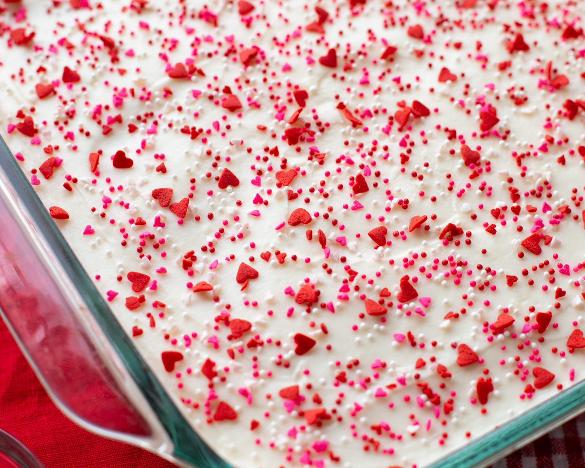 Red Velvet poke cake with sprinkles on it.