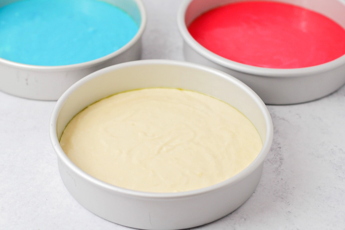 Cake batter colored red white and blue in three separate cake pans.