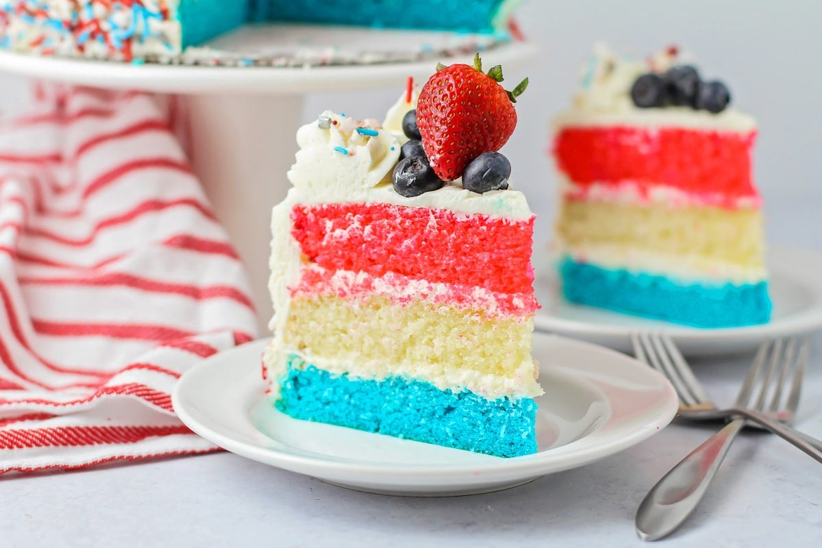 A slice of red white and blue cake topped with fresh berries.