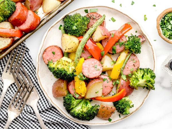 Sheet pan sausage and veggies served on a white plate.