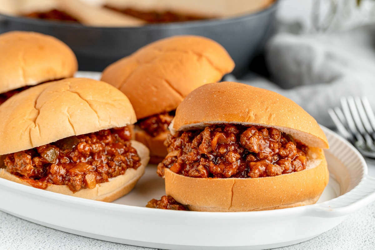 Close up of four sloppy joes served on a white plate.