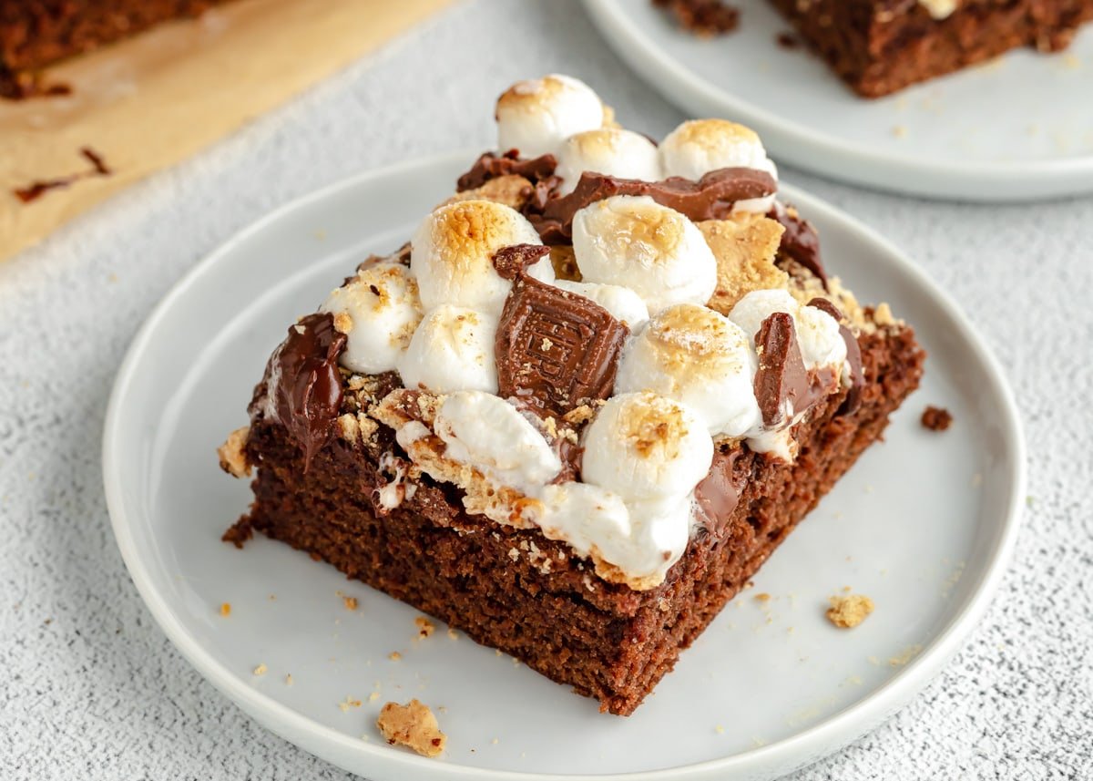 A square slice of s'mores brownies served on a white plate.