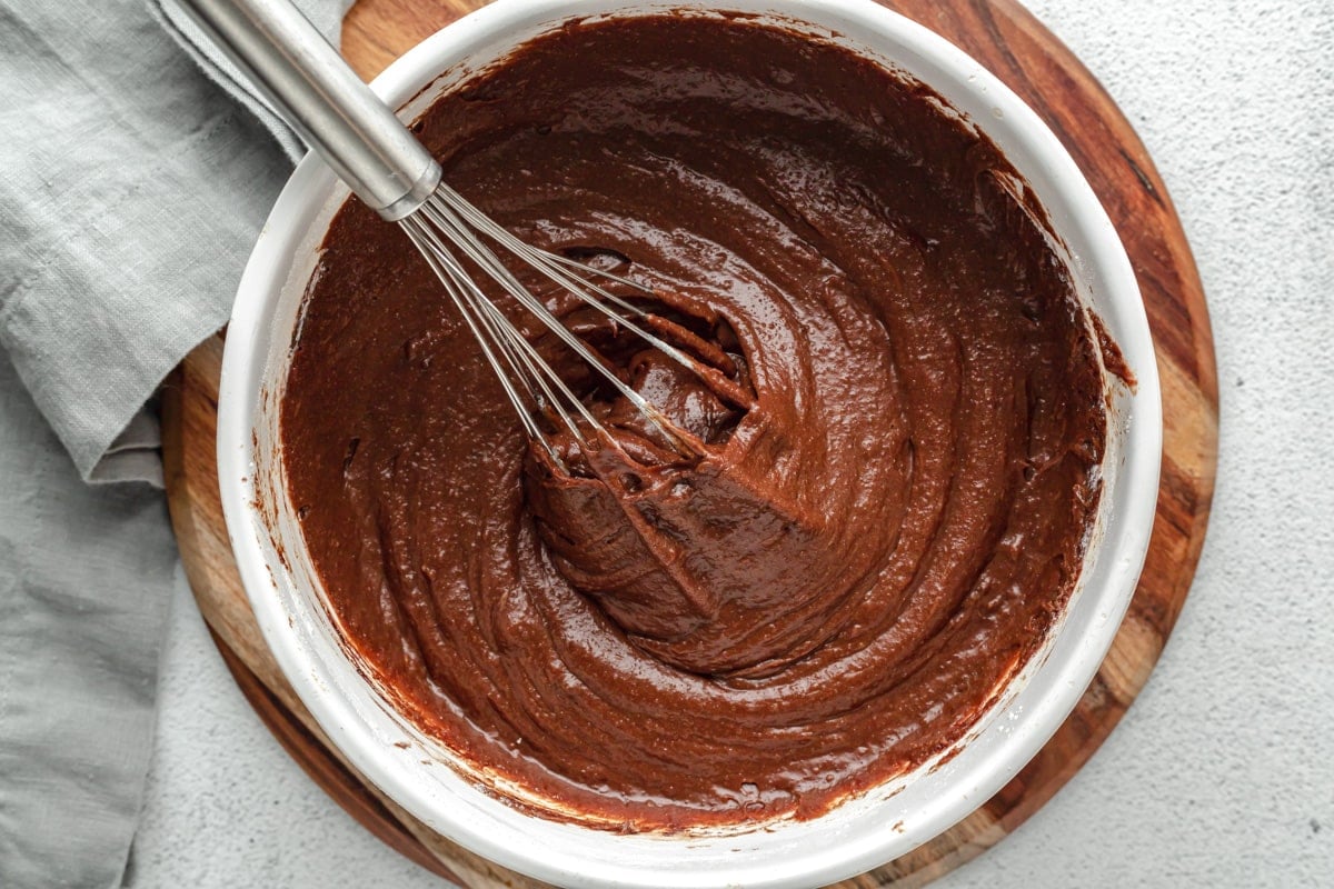 Mixing brownie batter in a white bowl.