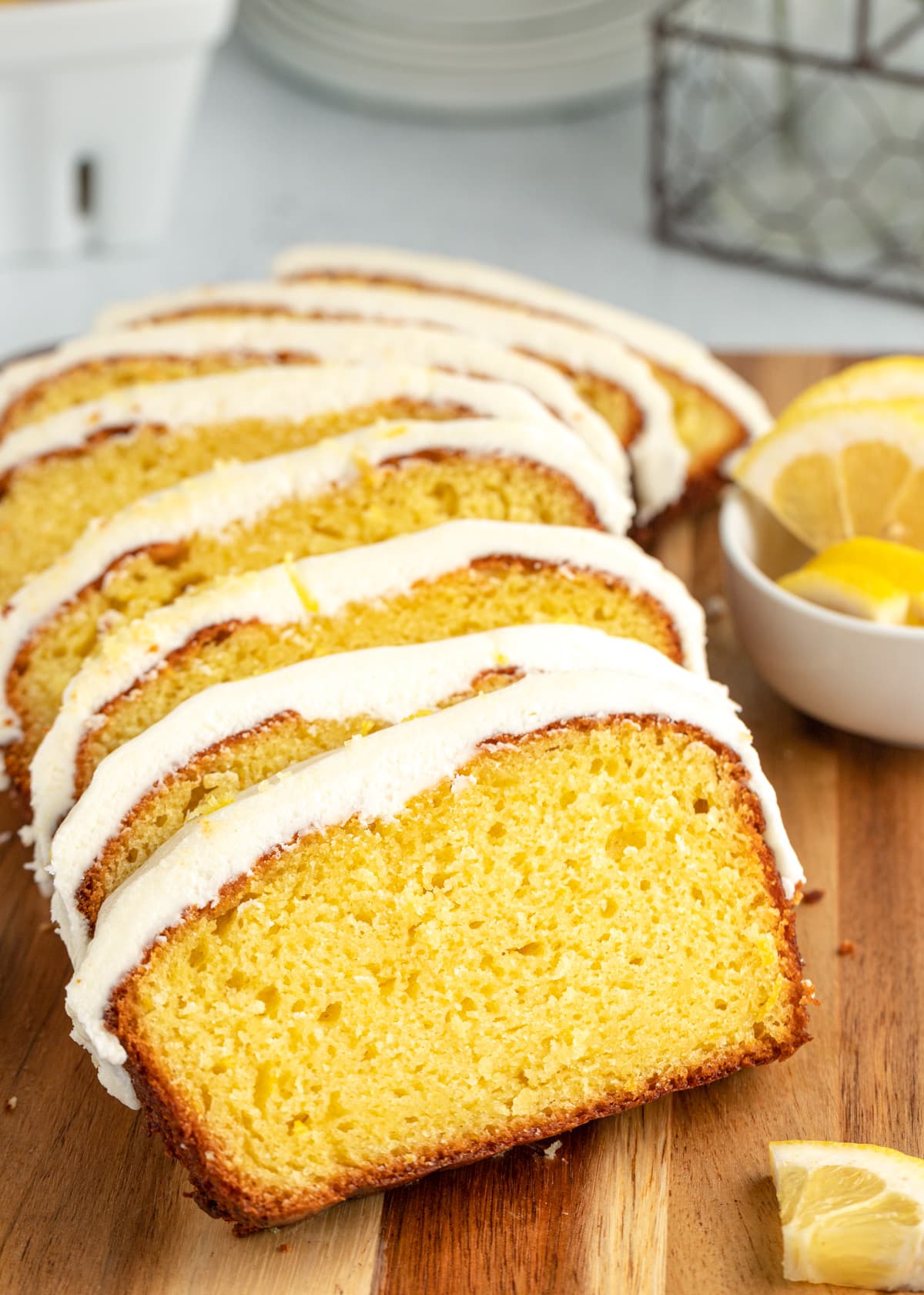 Close up of frosted slices of Starbucks lemon loaf cake on a cutting board.