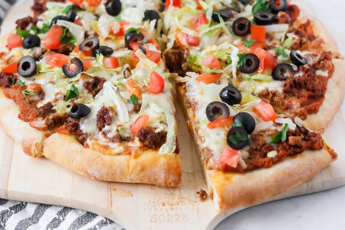 Taco pizza on cutting board cut and sliced.