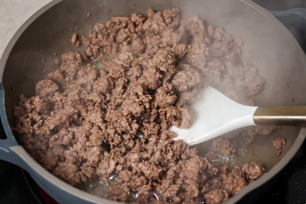 Hamburger meat cooking in skillet.