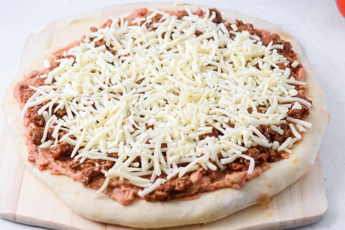 Taco pizza with toppings on it ready to be baked.
