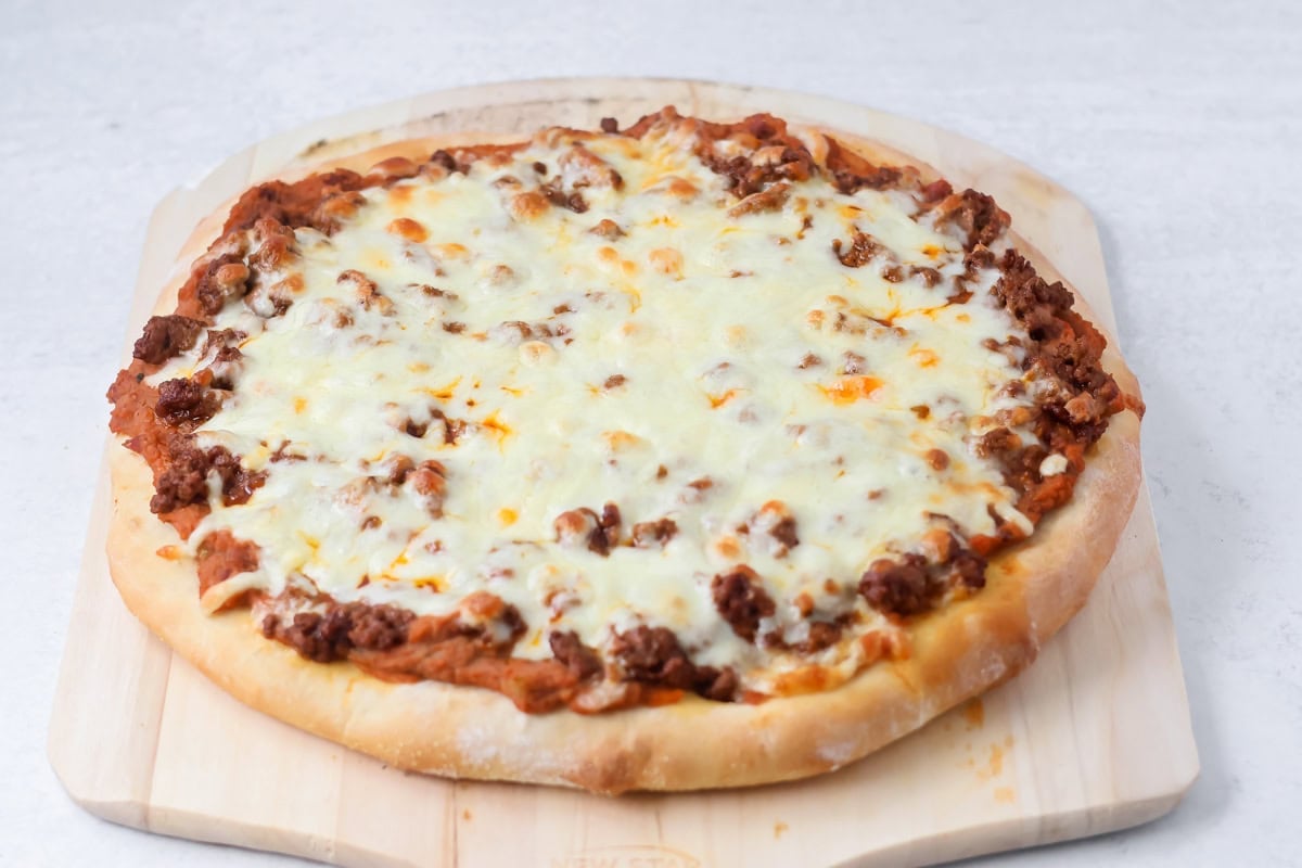 Baked taco pizza recipe on cutting board.