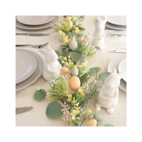 Decorated table top with a garland with eggs and bunny decorations in the middle of it.