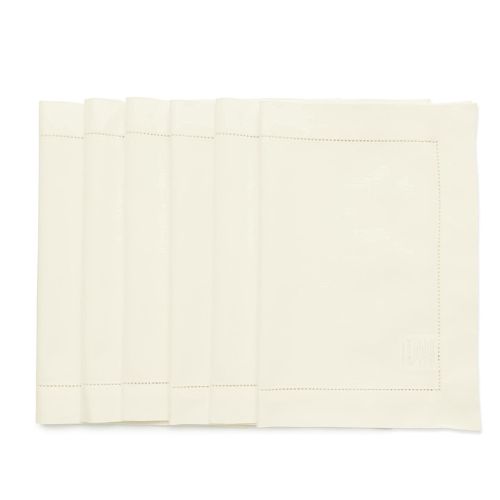 Six off white placemats folded in half and stacked on top of each other.
