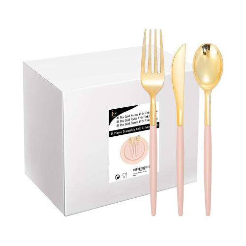 An upright plastic pink and gold fork, knife and spoon in front of a box with more of the same utensils.