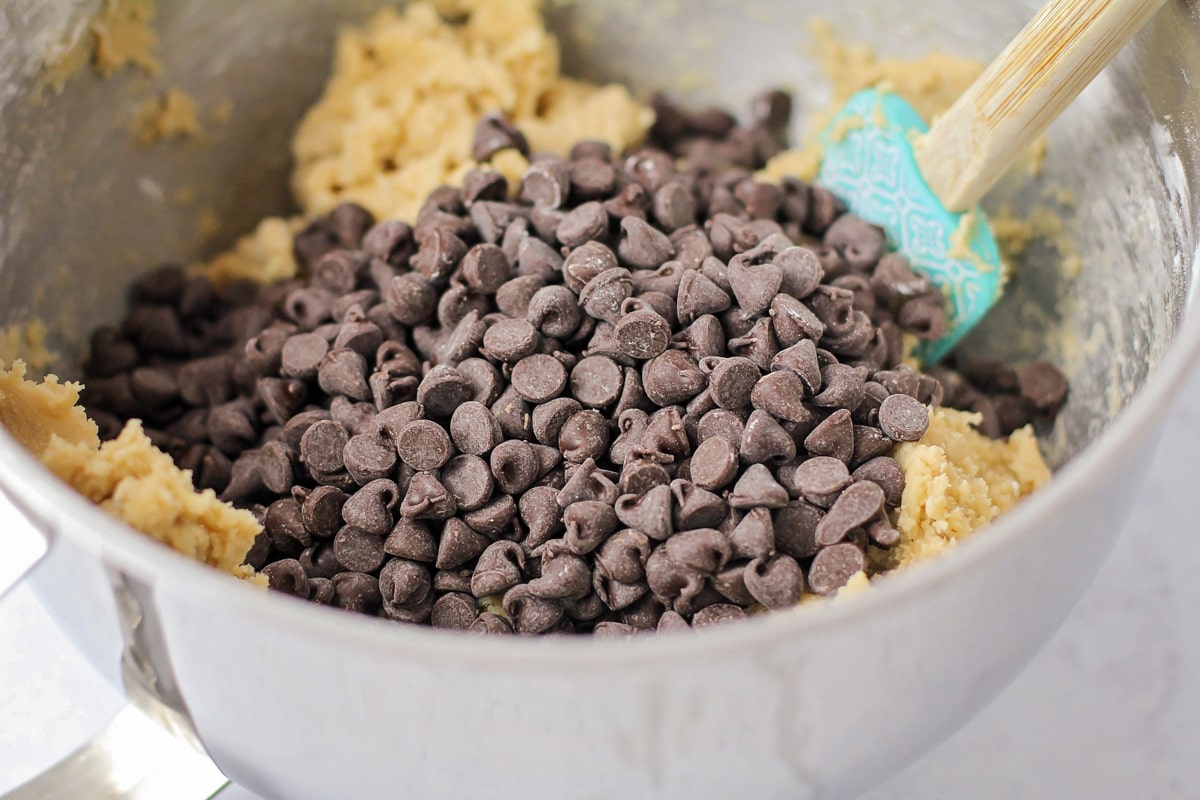 Adding chocolate chips to the cookie dough batter.