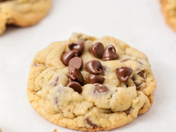 A bakery style chocolate chip cookie on a lined baking sheet.