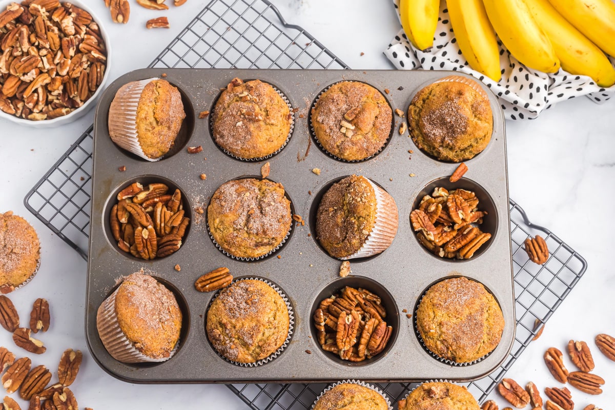Banana nut muffins in a muffin tin with pecans.