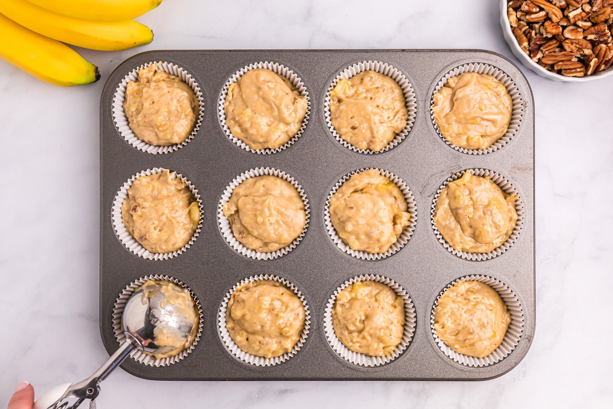 Scooping batter into a lined muffin tin.