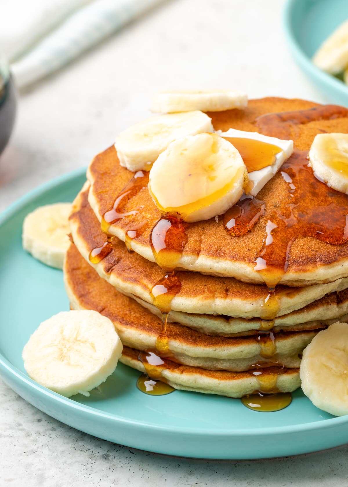 How to make banana pancakes - stacked and topped with sliced bananas and syrup.