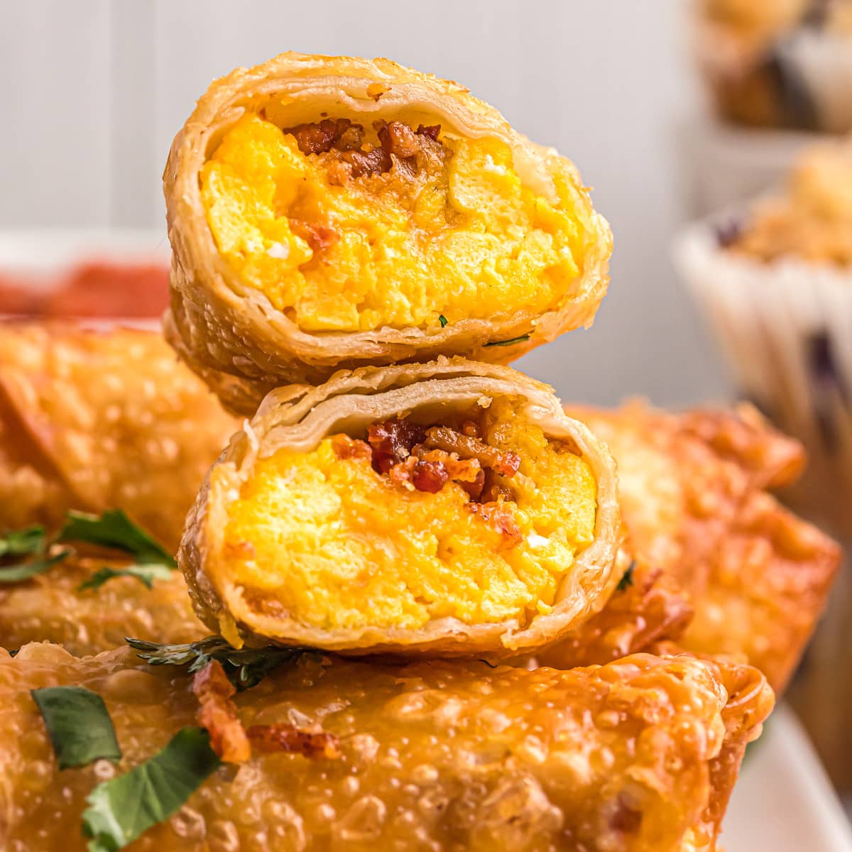 A crispy breakfast egg roll cut in half and stacked on other egg rolls.