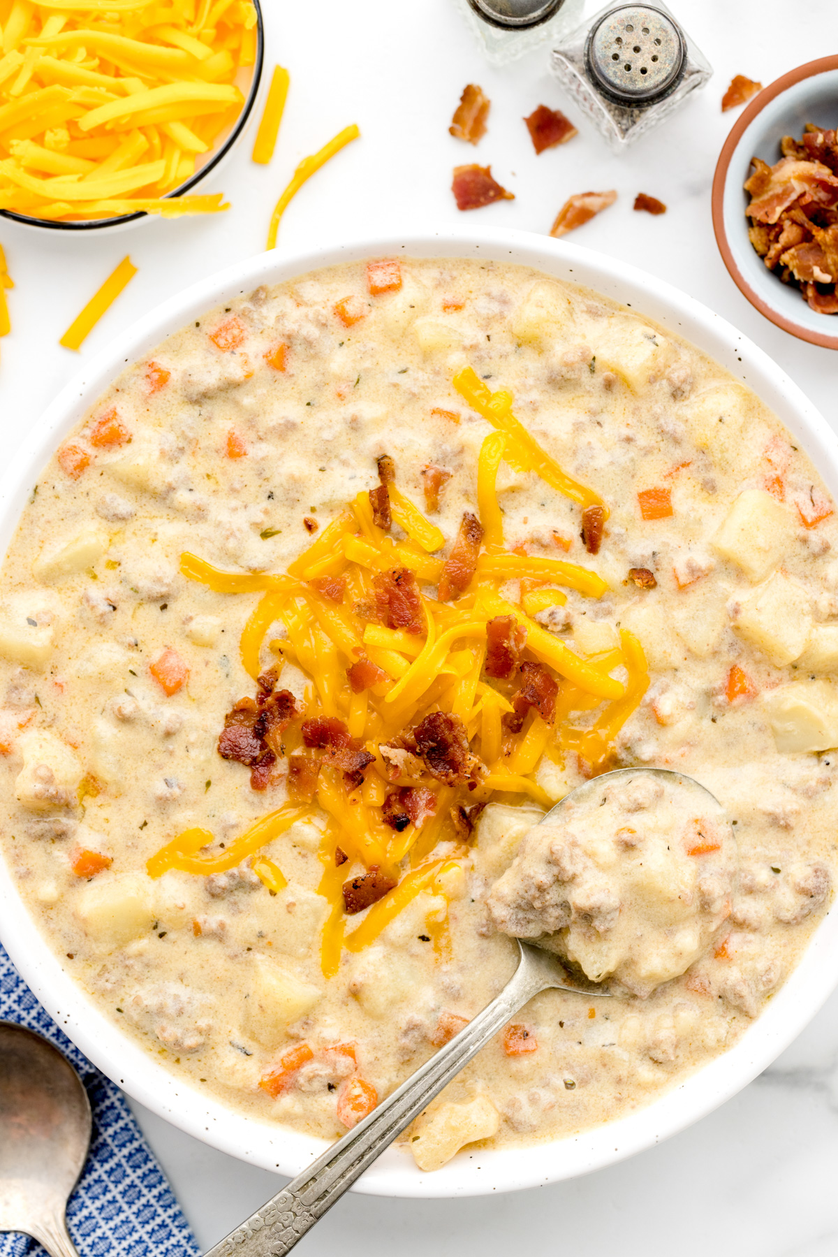 A bowl of cheeseburger soup topped with cheeese and bacon crumbles.