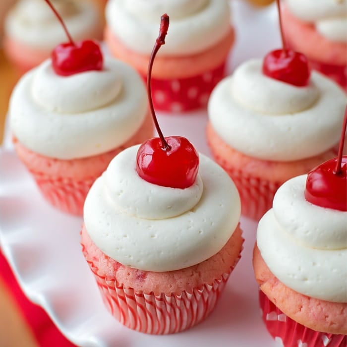 Cherry almond cupcakes on white cake stand.