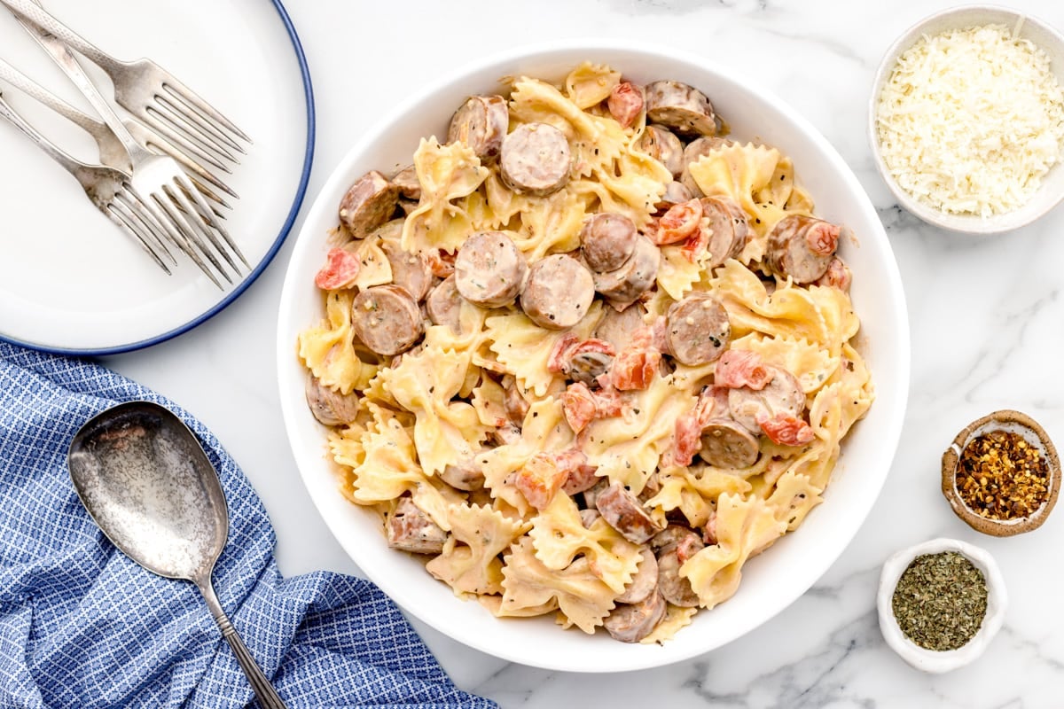 A white bowl filled with creamy chicken sausage pasta.