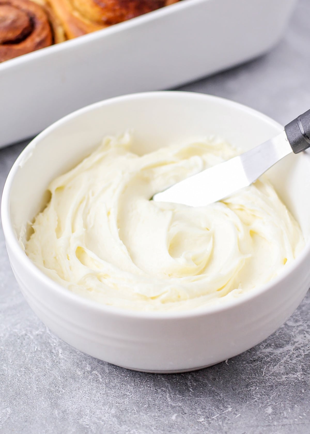 A white bowl filled with cream cheese icing.