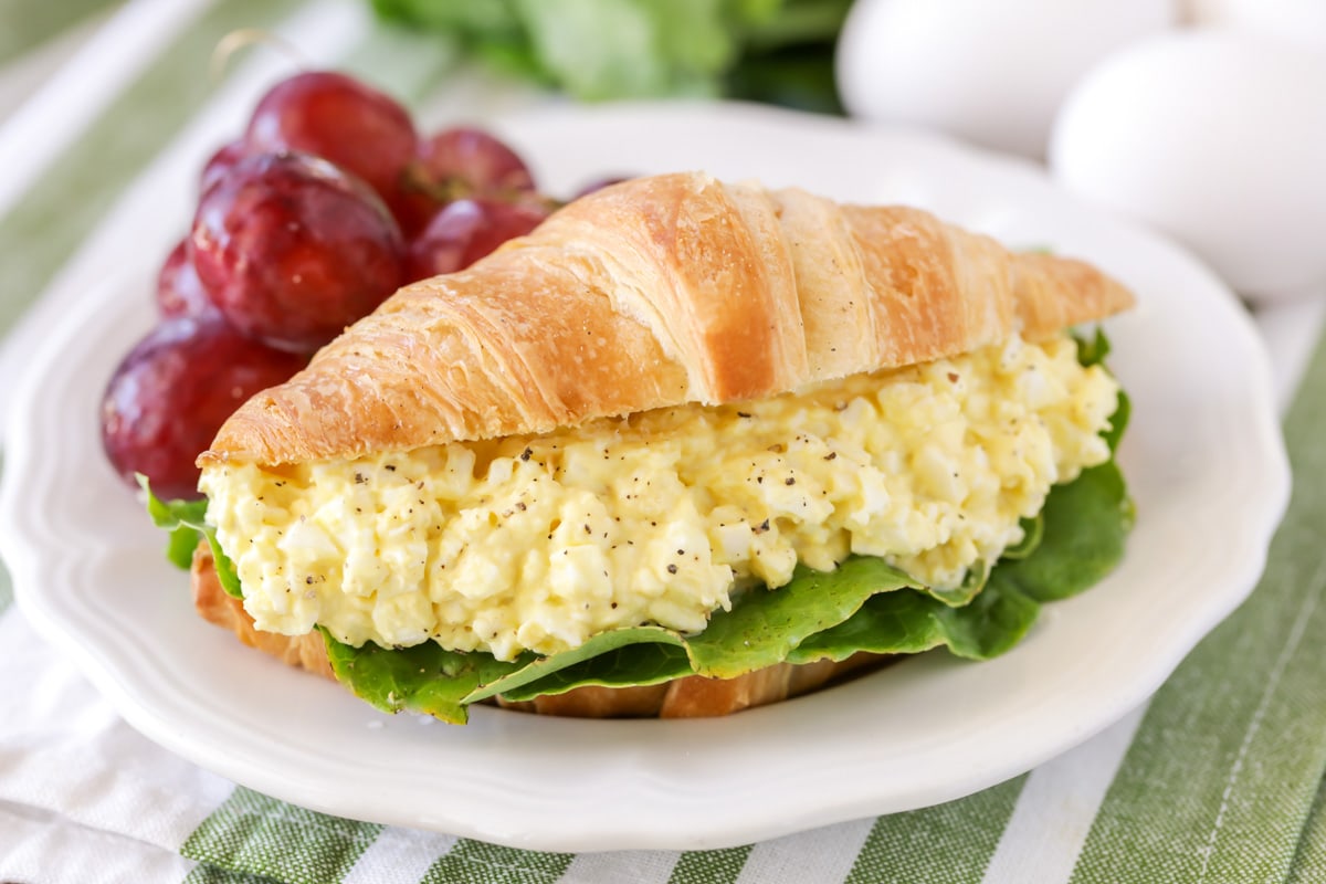 How to make egg salad, served on a croissant sandwich with grapes.