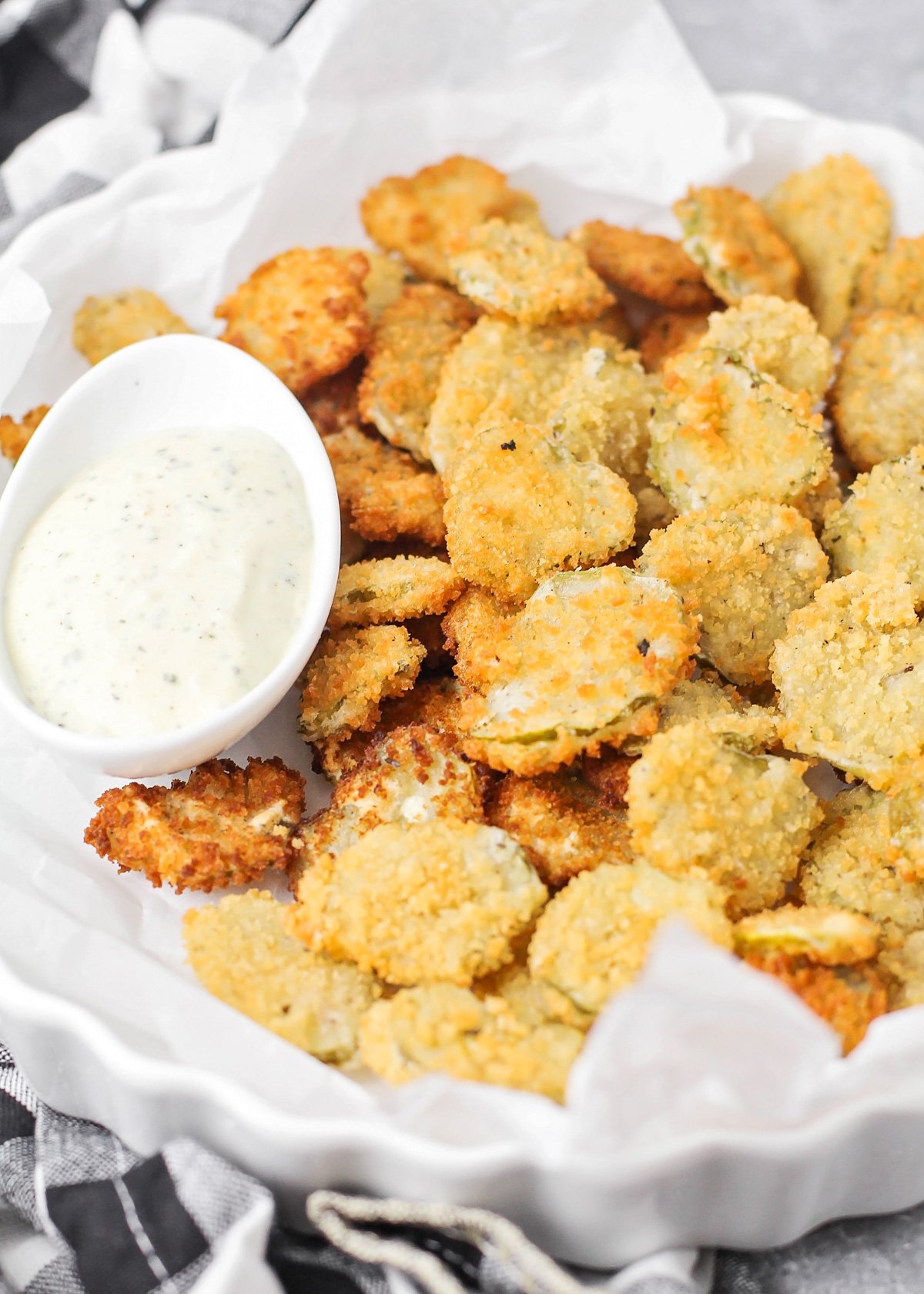 Close up of deep fried pickles on a plate with ranch dressing.