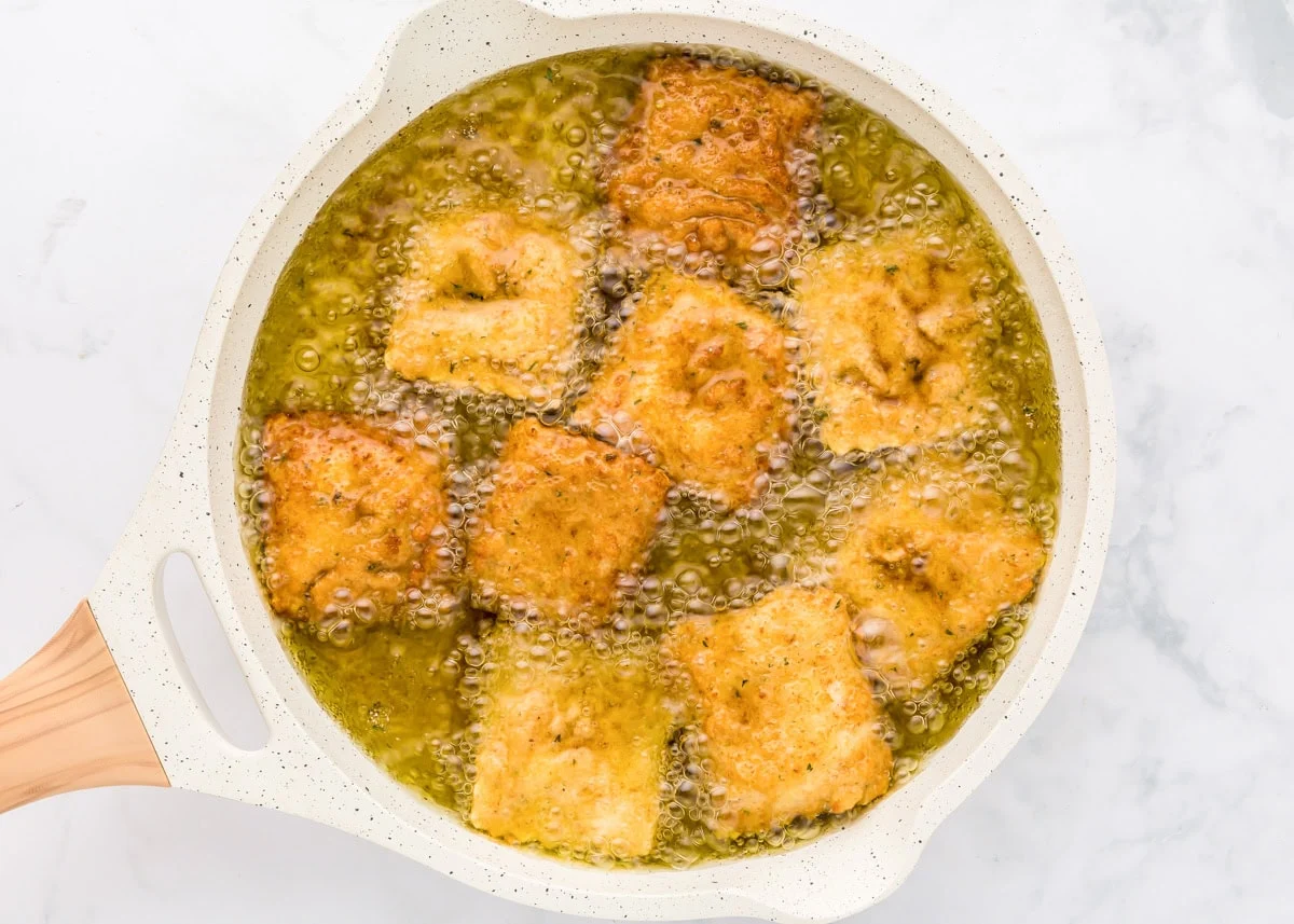 Frying ravioli in a pan of oil.