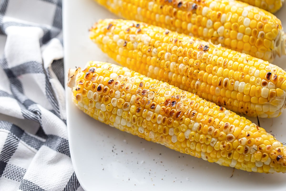 Grilled corn the cob served on a white plate.