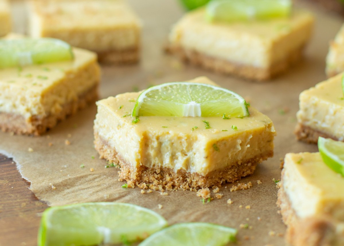Key lime pie bars topped with lime slices with a bite missing.