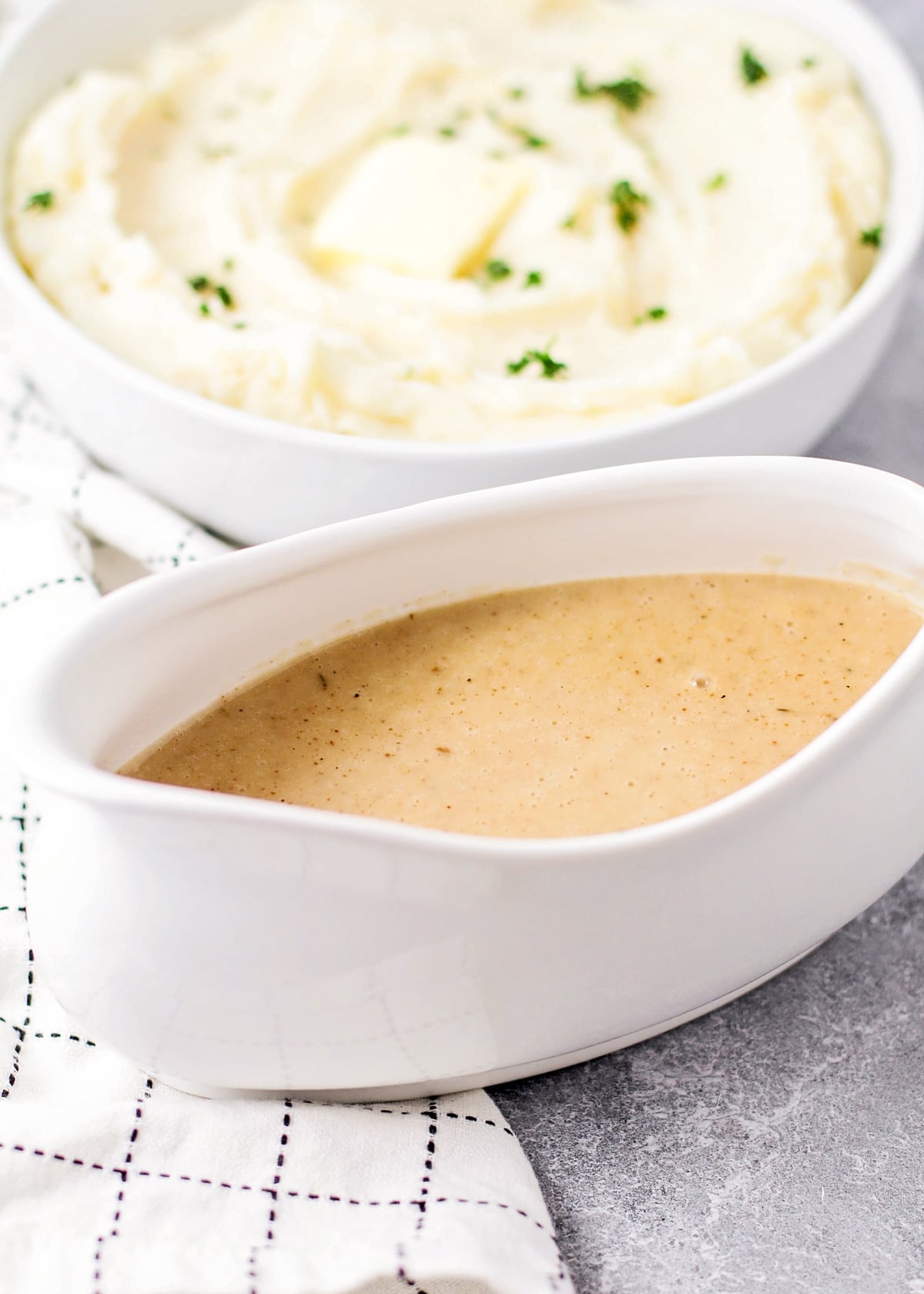 Mashed potato gravy served in a bowl next to mashed potatoes.