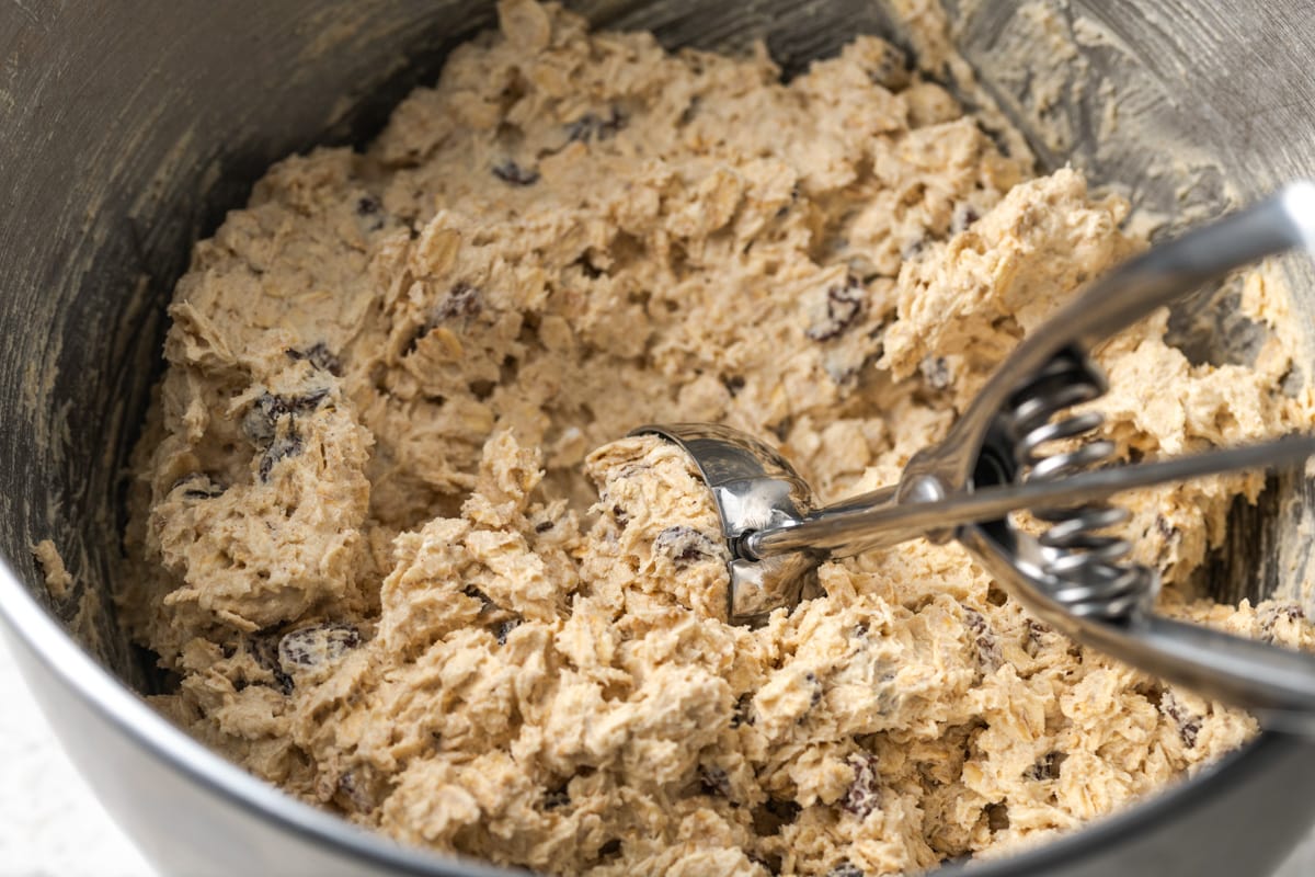 Scooping easy oatmeal raisin cookies into balls for baking.